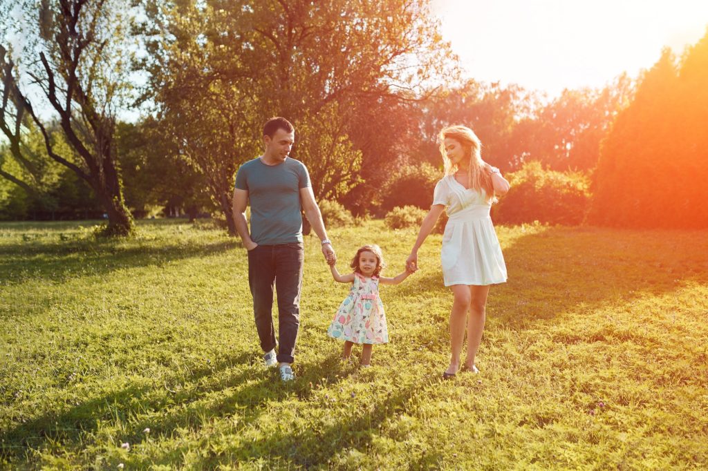 Happy young family spending time together outside in green nature.